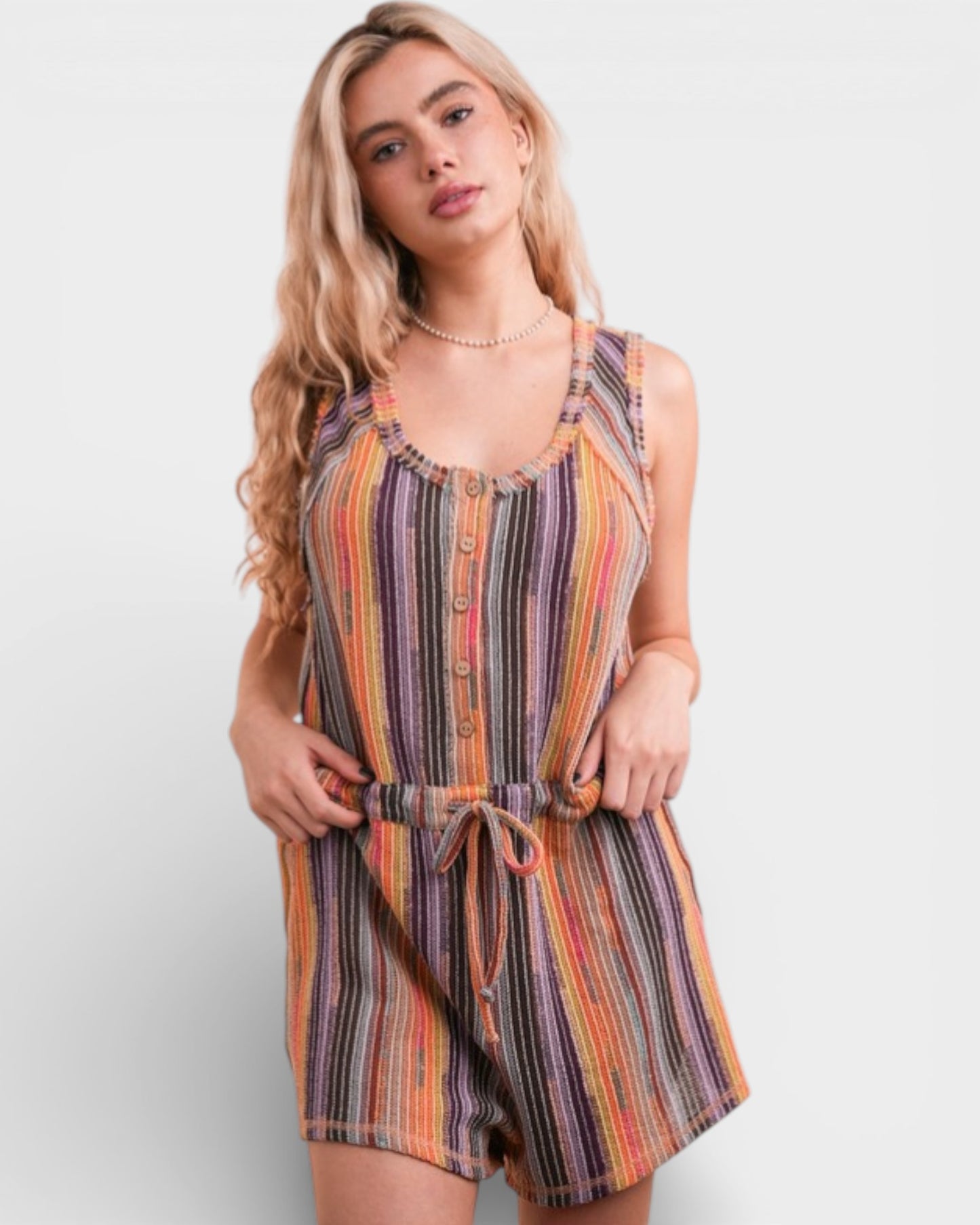 Woman wearing a colorful striped romper on a plain background