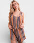 Woman wearing a colorful striped romper on a plain background