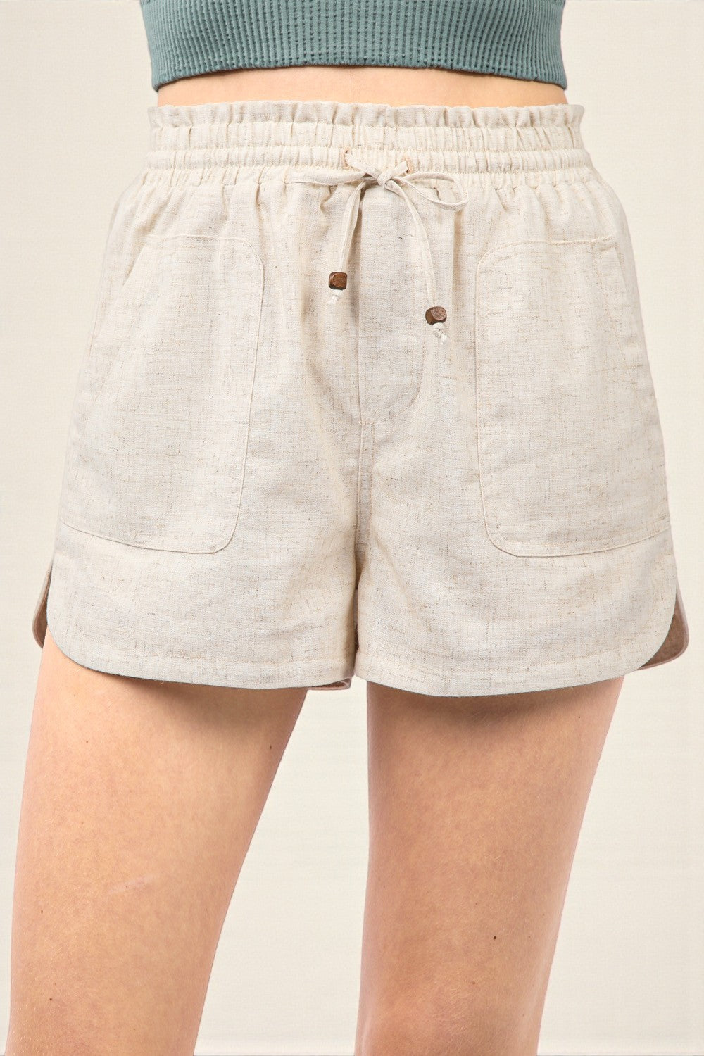 Beige shorts with drawstring and button details on a plain background