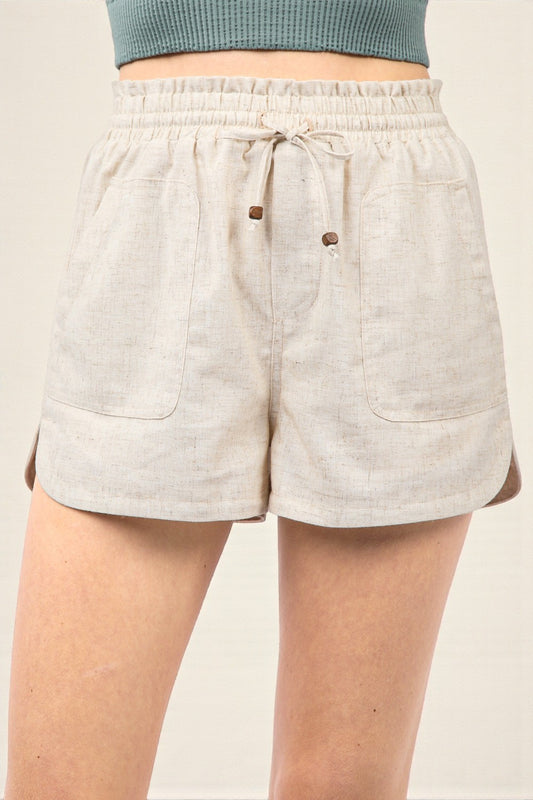Beige shorts with drawstring and button details on a plain background