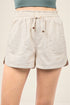 Beige shorts with drawstring and button details on a plain background