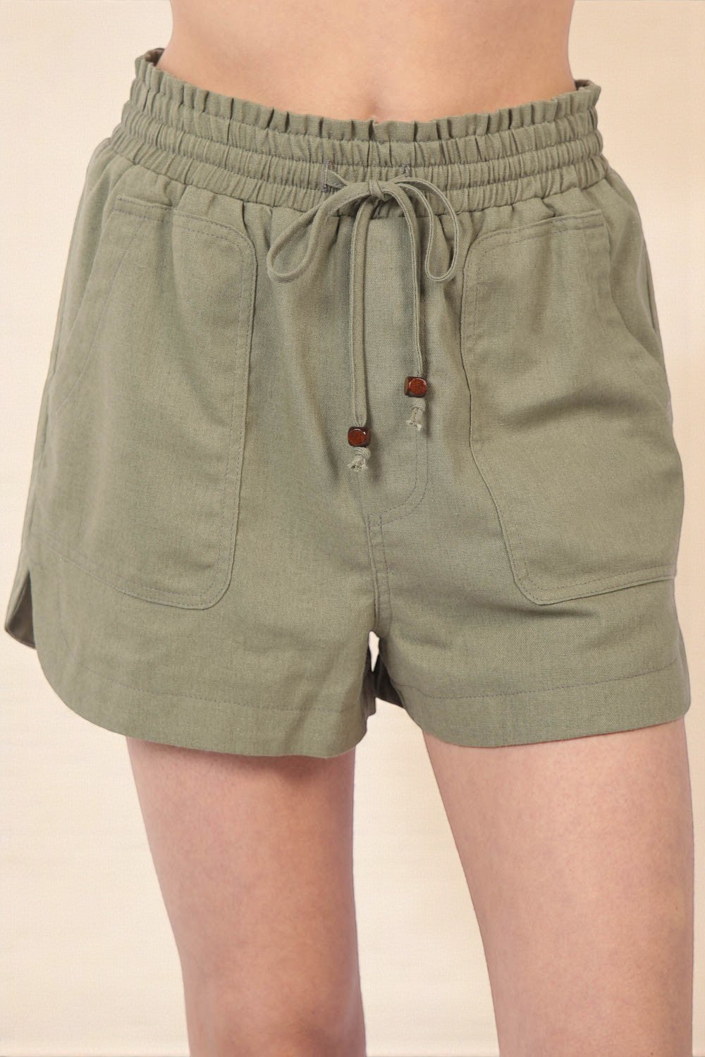 Green shorts with drawstring waist on a beige background