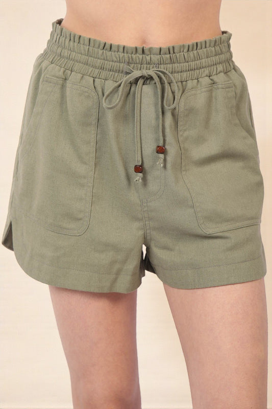 Green shorts with drawstring waist on a beige background