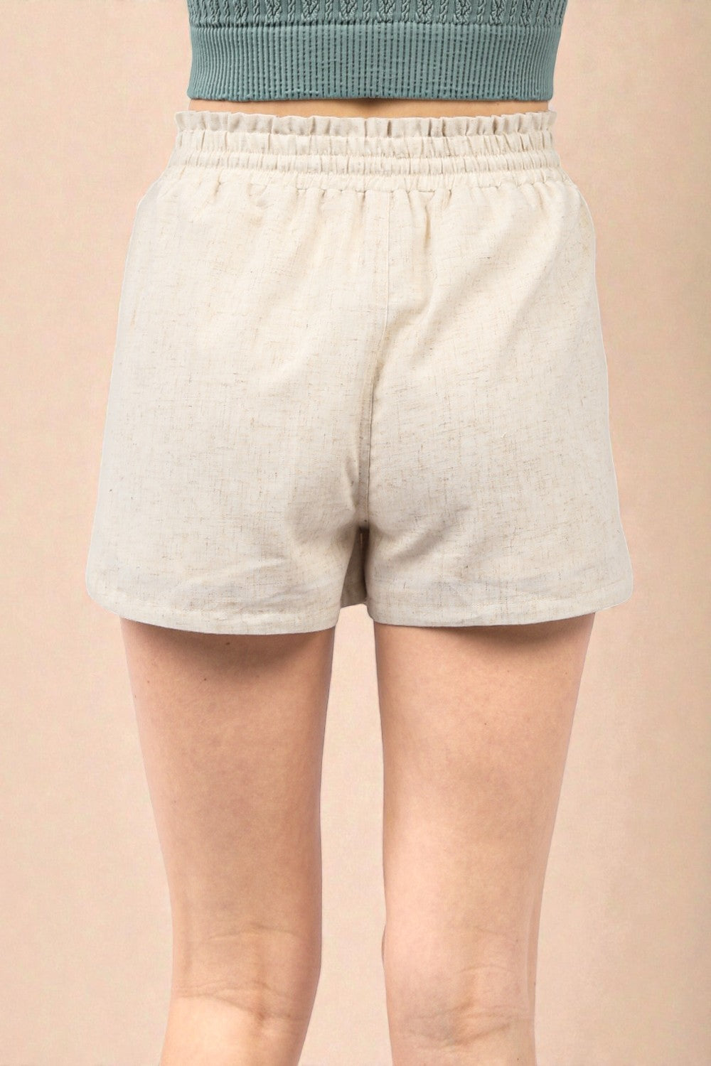 Person wearing light gray shorts on a beige background