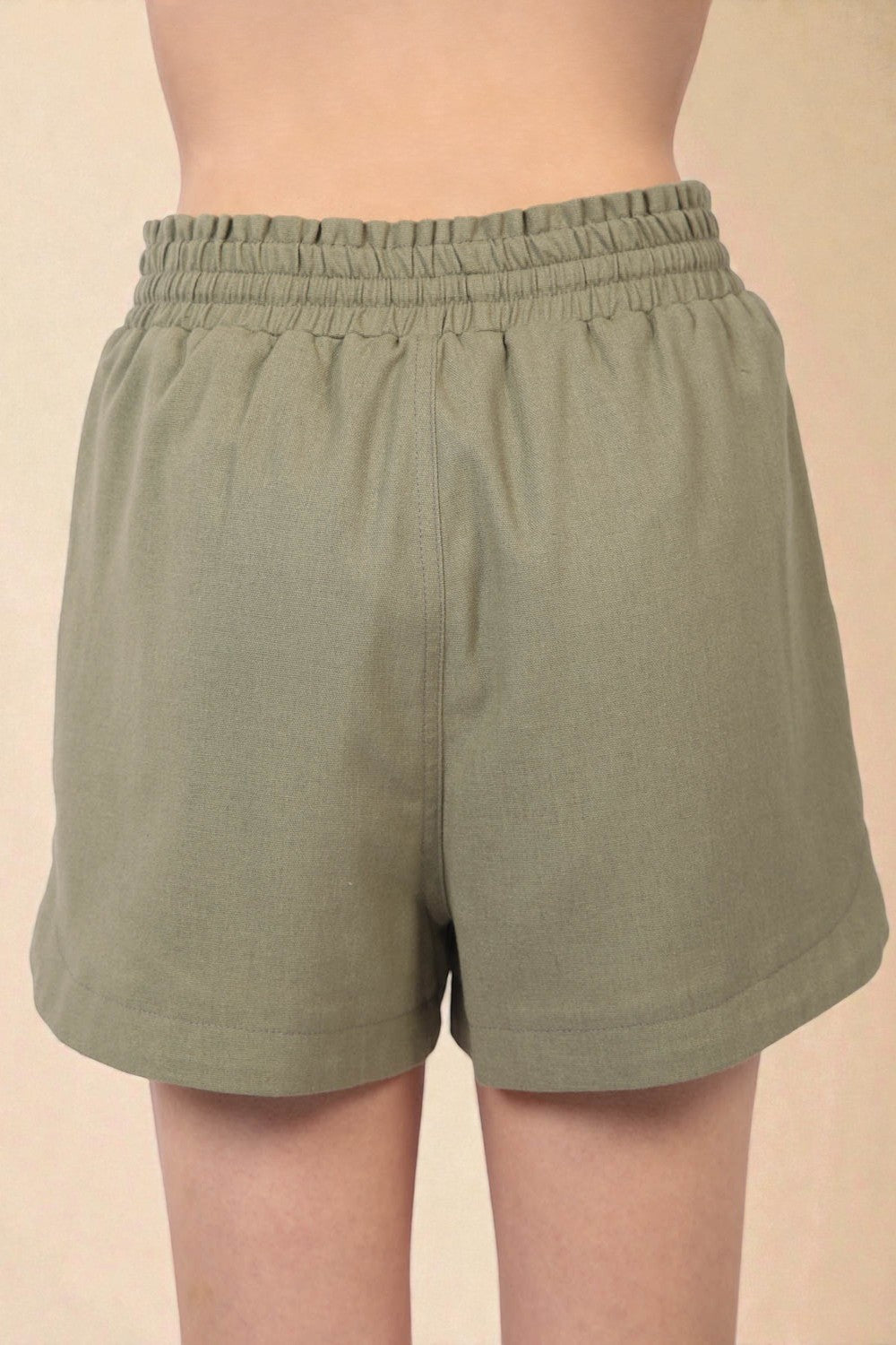 Green shorts worn by a person on a beige background