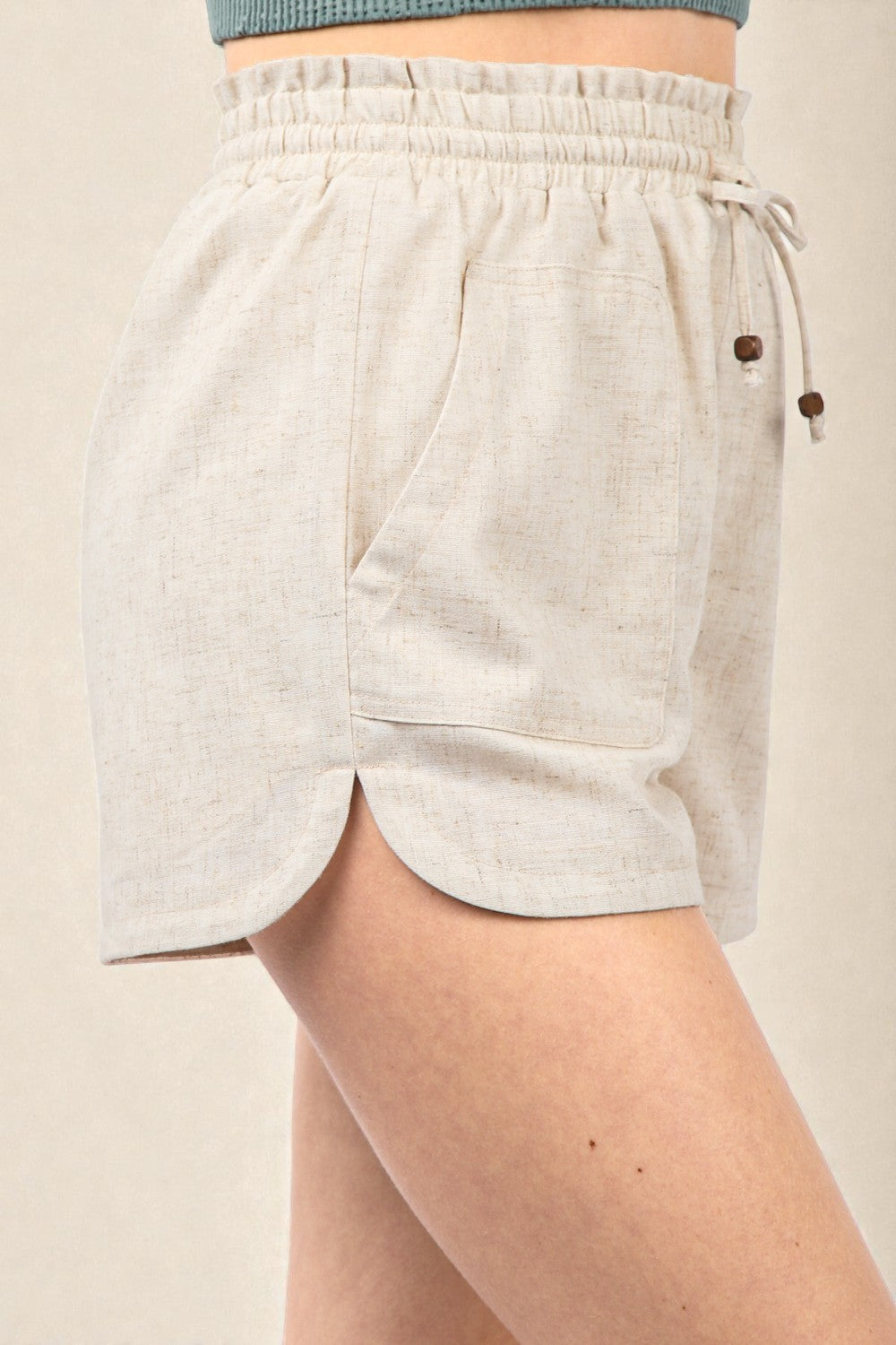 Beige shorts with drawstring and buttons on a beige background