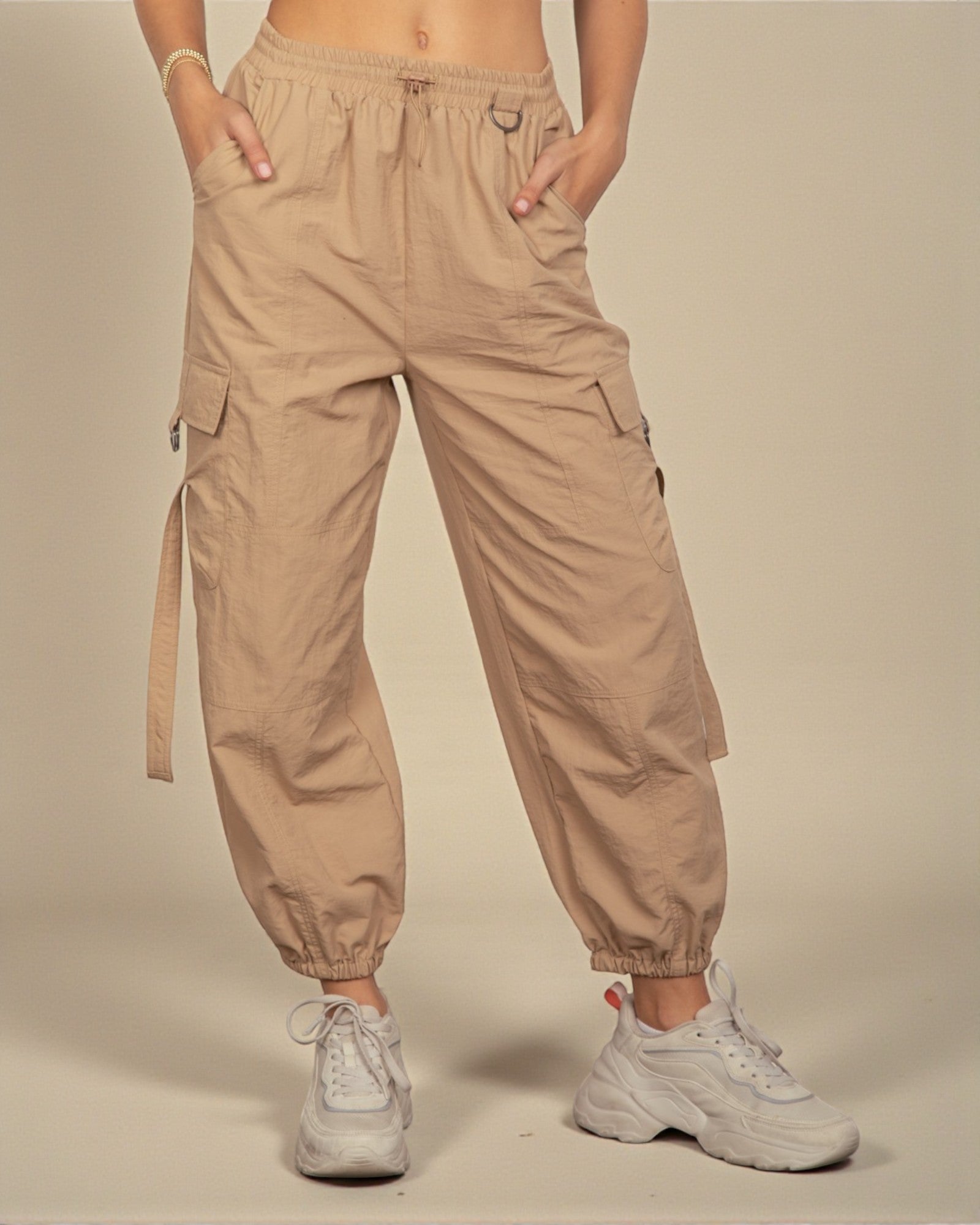 Person wearing beige cargo pants with a plain background