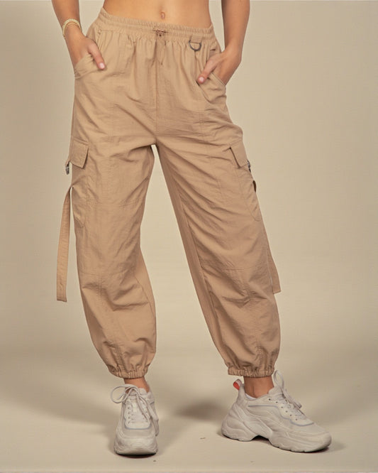 Person wearing beige cargo pants with a plain background