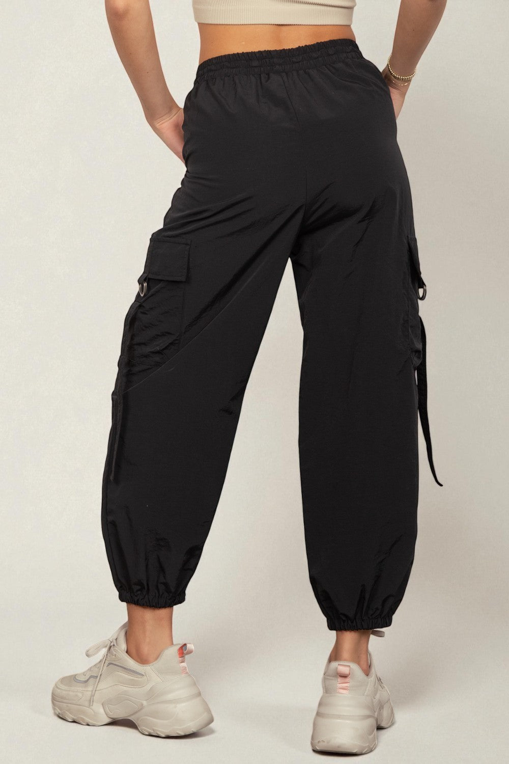 Person wearing black cargo jogger pants on a plain background
