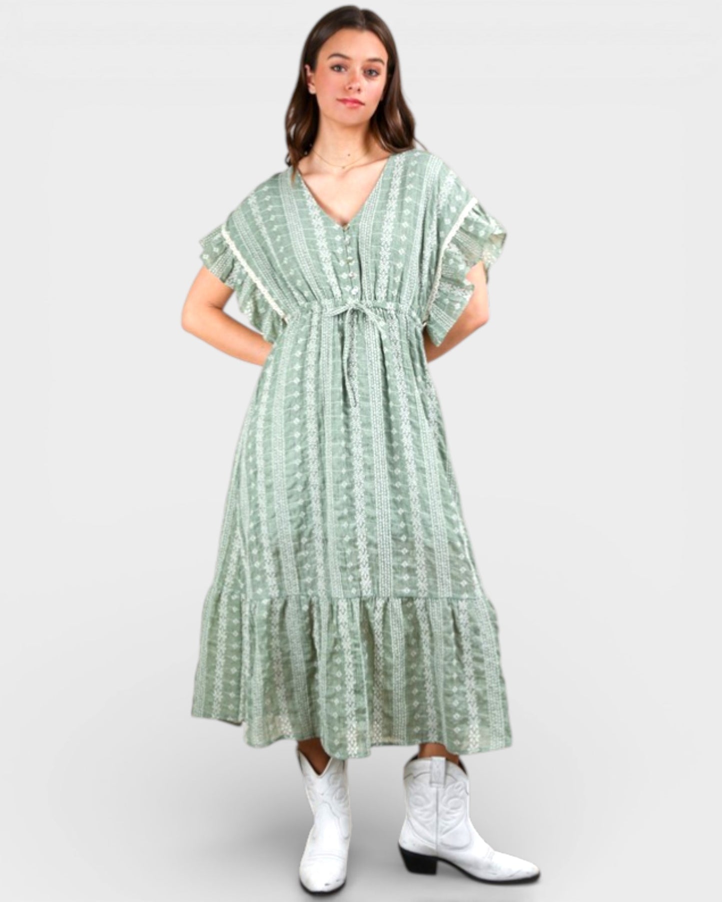 Woman wearing a green patterned dress with white boots on a white background