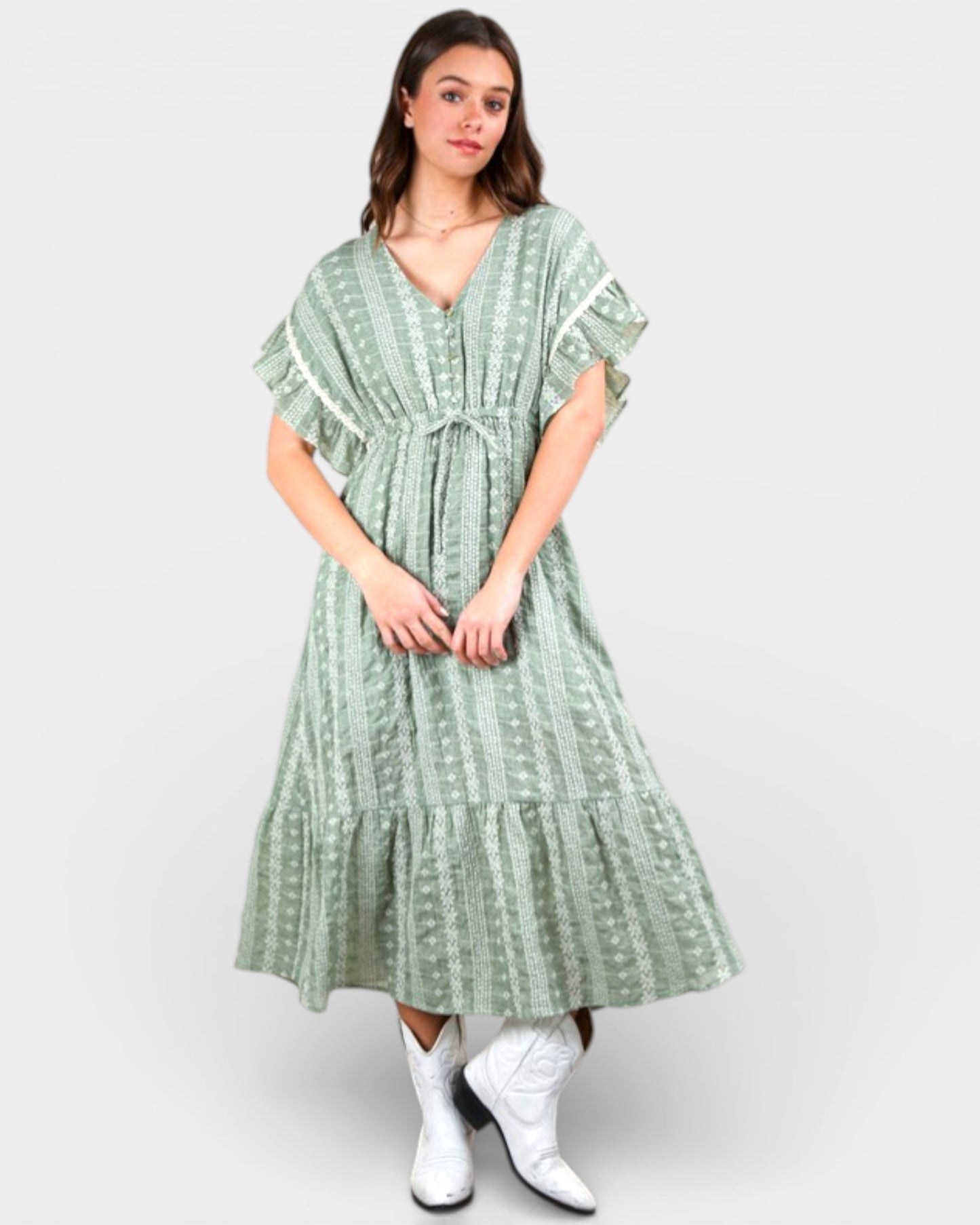 Woman wearing a green patterned dress with white boots on a light gray background