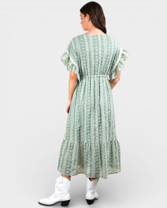 Woman wearing a green patterned dress with white boots on a white background