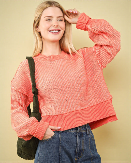 Woman wearing a pink sweater and blue jeans against a yellow background