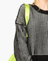 Close-up of a person wearing a black and white vertically striped knit sweater with a bright neon green shoulder strap and a matching neon green quilted bag visible against a light gray background.