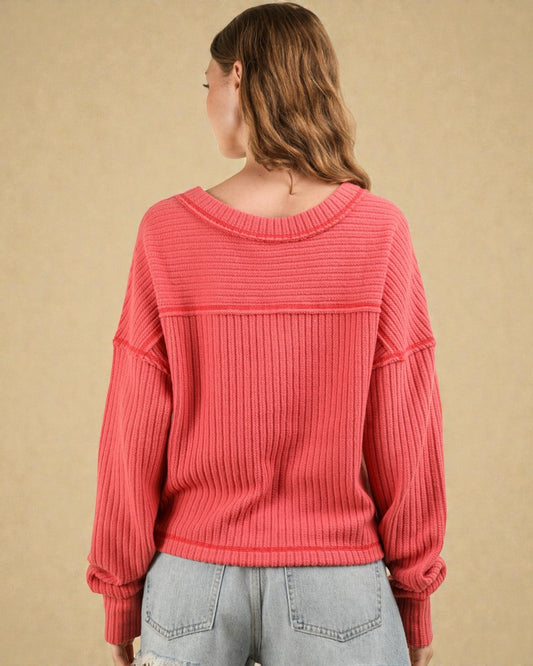 Person wearing a pink ribbed sweater against a beige background