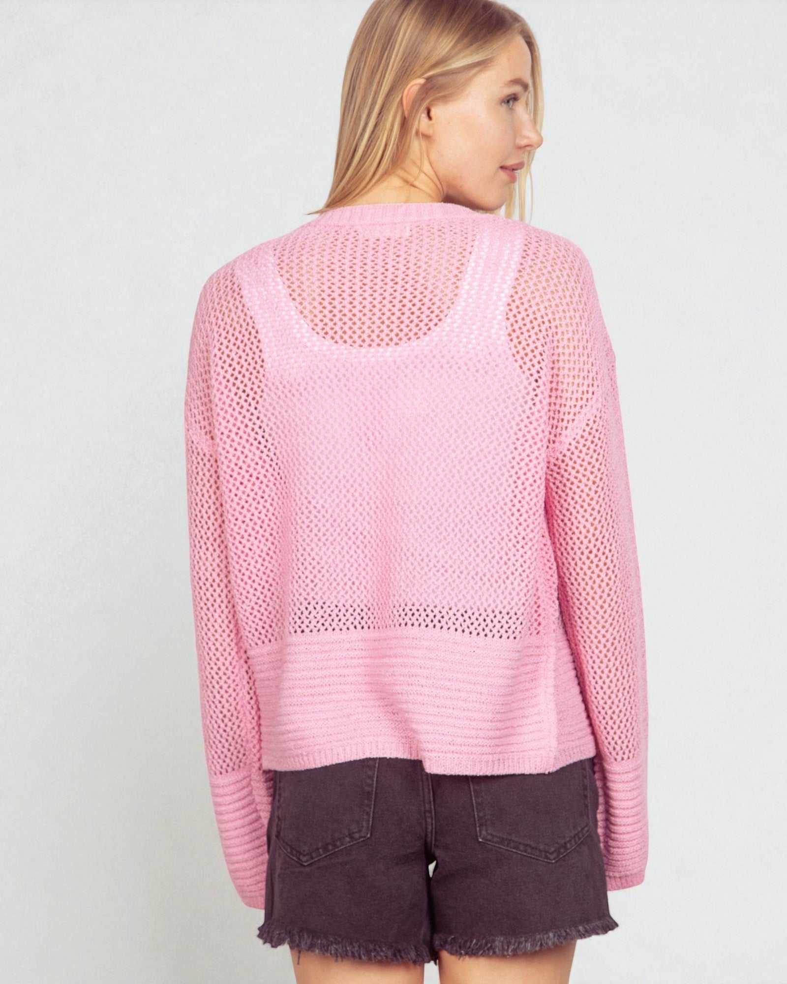 Woman wearing a pink knit sweater with a plain background
