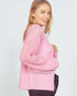 Woman wearing a pink knitted sweater on a plain background