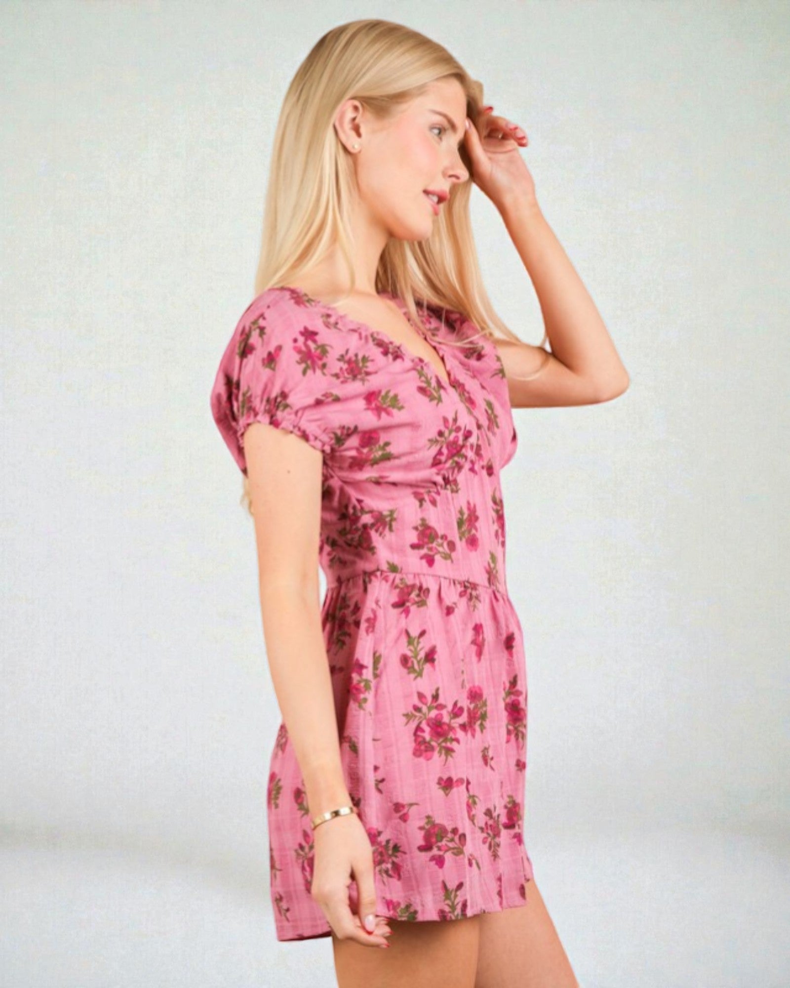 Woman wearing a pink floral dress against a plain background
