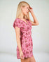 Woman wearing a pink floral dress against a plain background