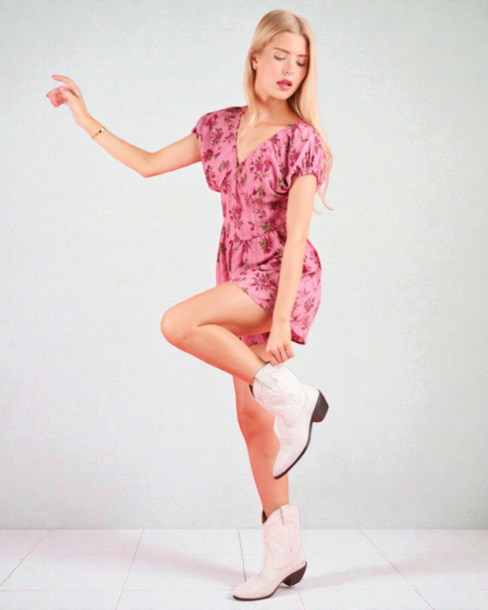 Woman wearing a pink floral dress and white boots on a light gray background