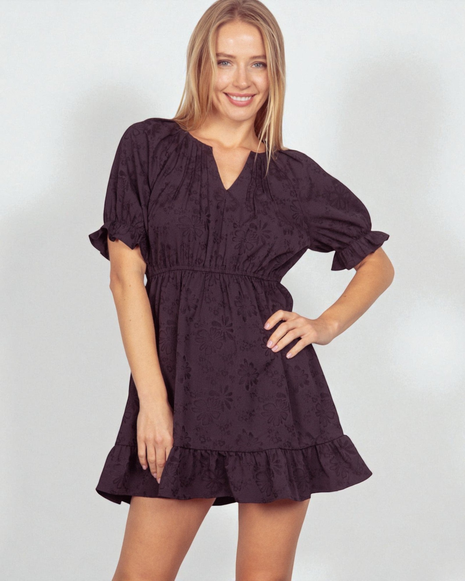 Woman wearing a dark purple dress with floral patterns on a white background