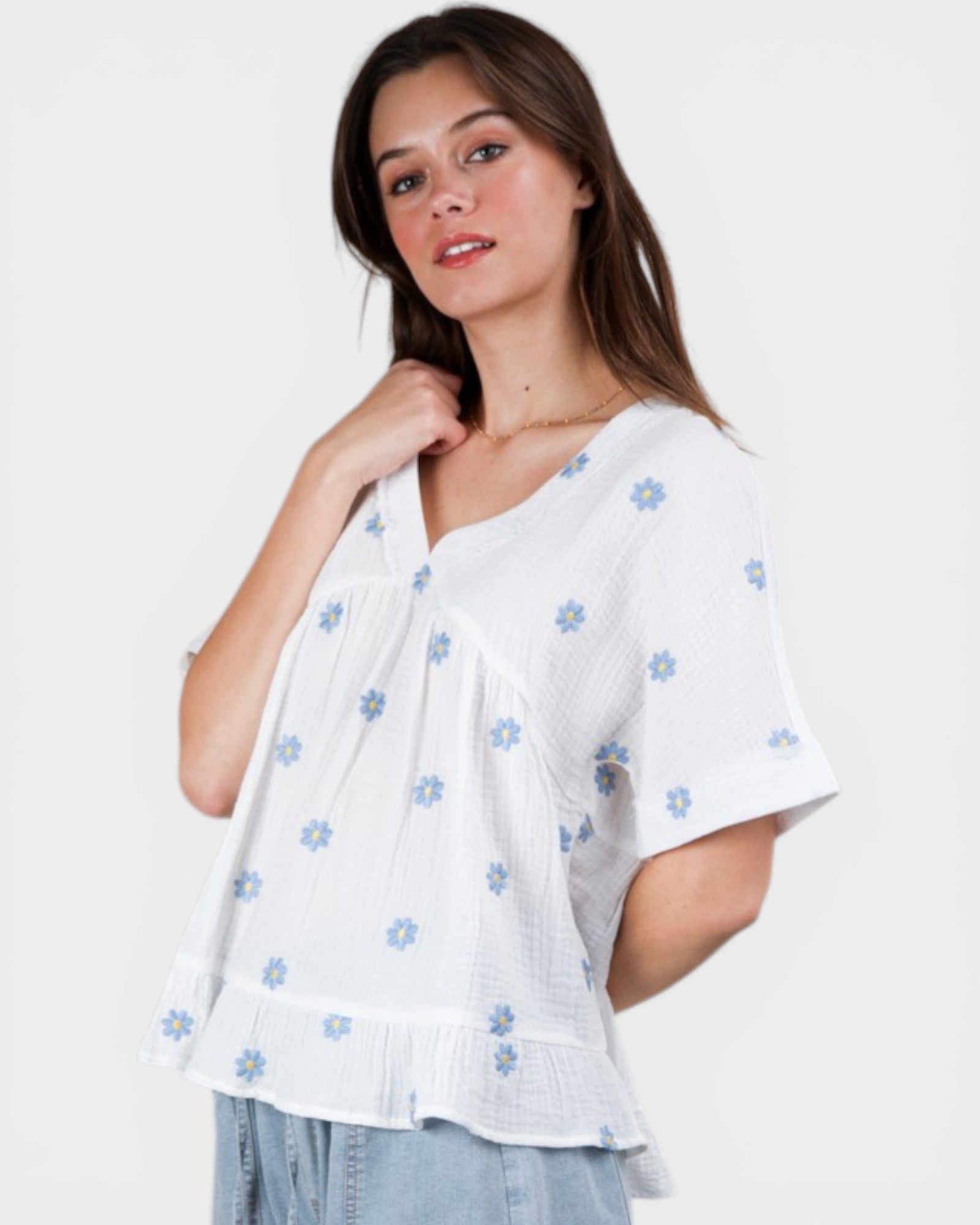 Woman wearing a white blouse with blue floral patterns on a white background