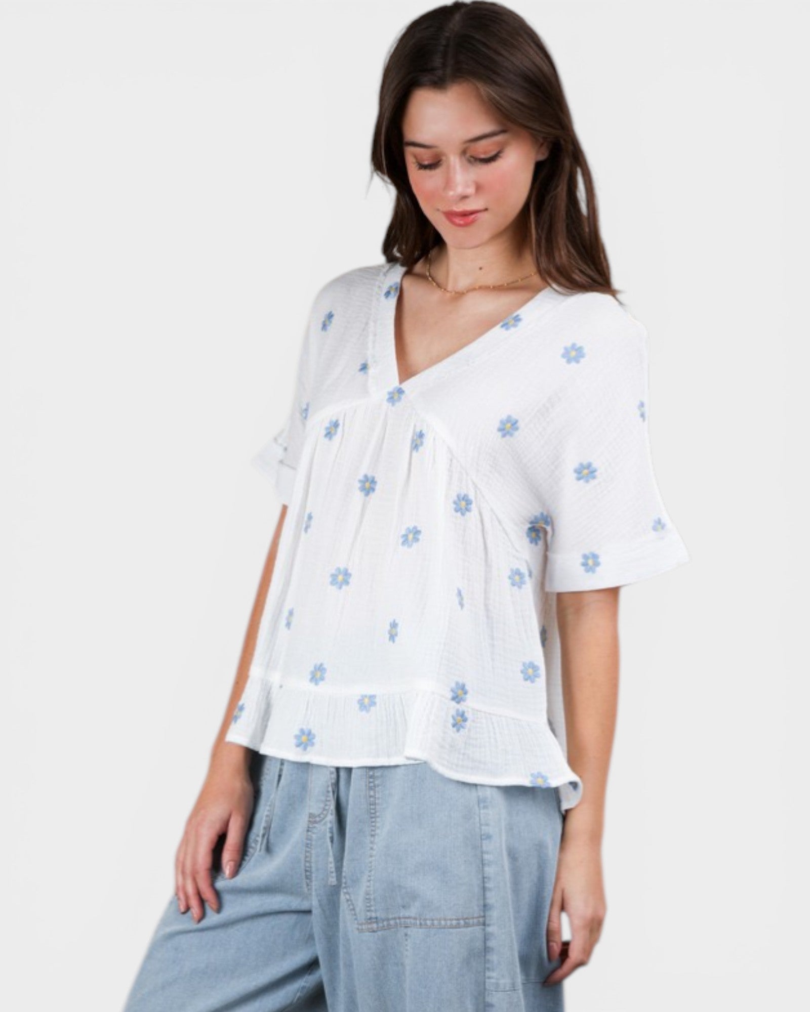 Woman wearing a white blouse with blue floral patterns on a plain background