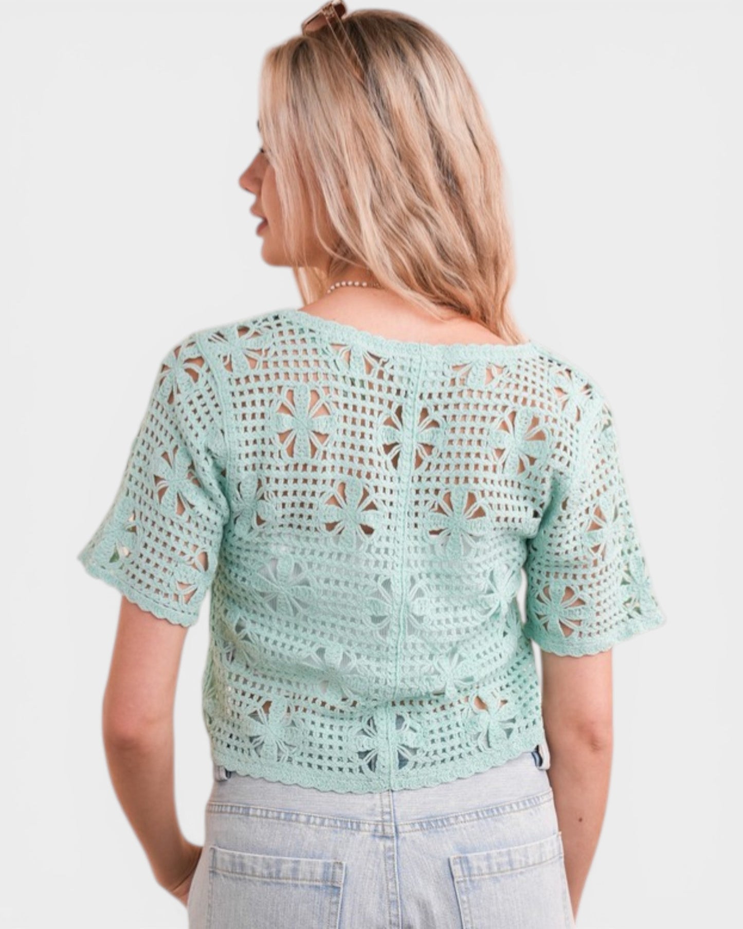 Woman wearing a light green crochet top on a white background