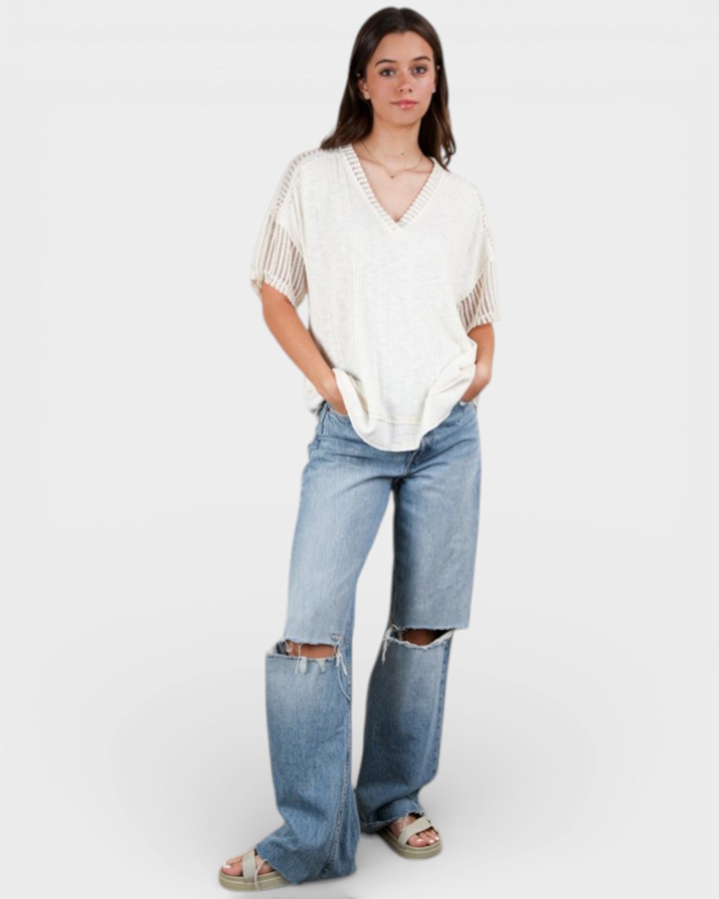 Woman wearing a white top and ripped blue jeans on a white background