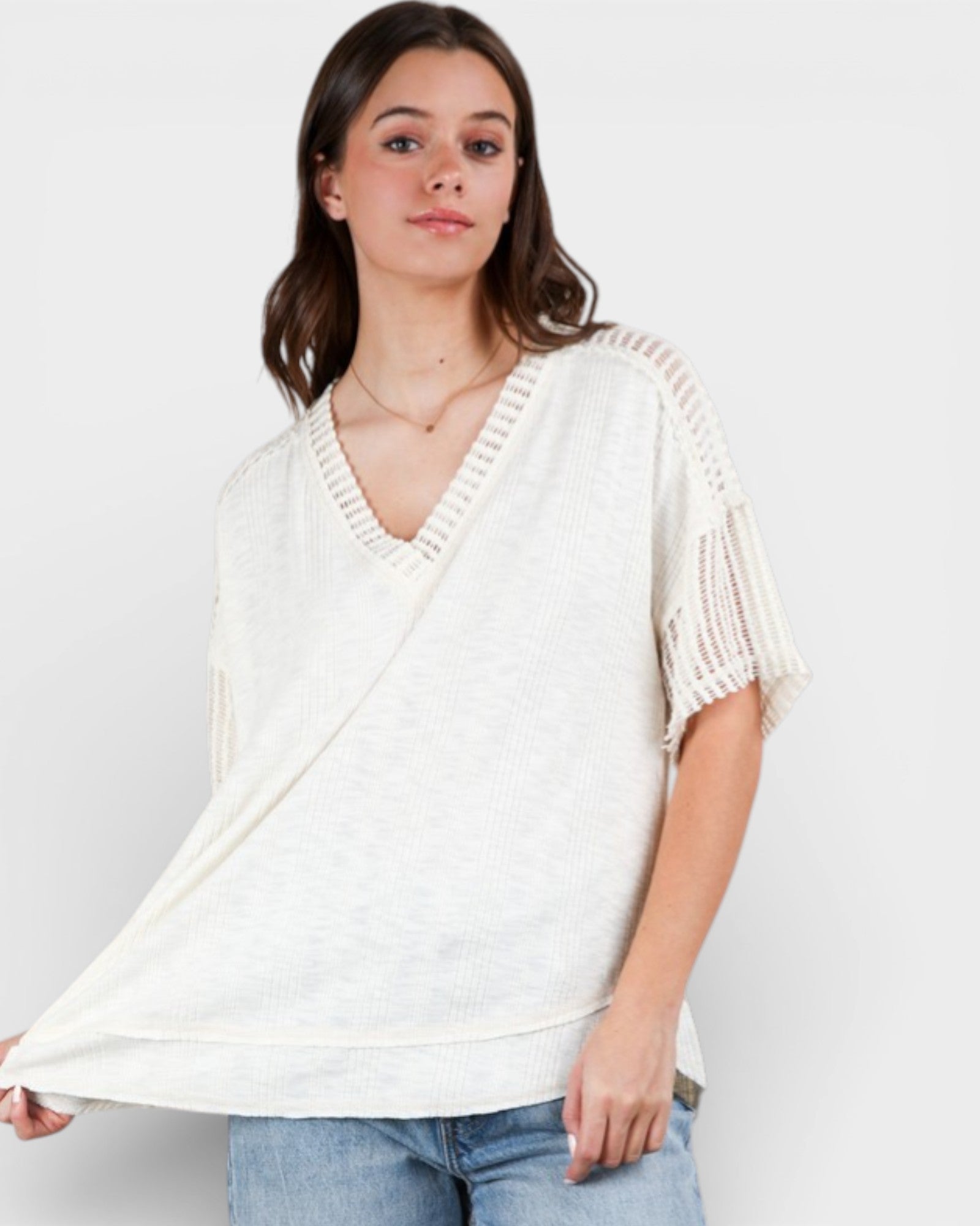 Woman wearing a white knit top with a plain background