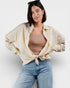 Woman wearing a beige shirt over a sheer top and blue jeans on a white background