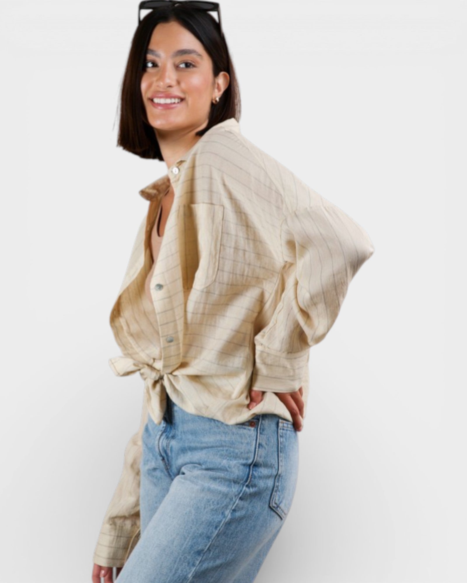 Woman wearing a beige checkered shirt and blue jeans on a white background