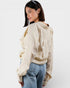 Woman wearing a beige sweater and blue jeans on a white background