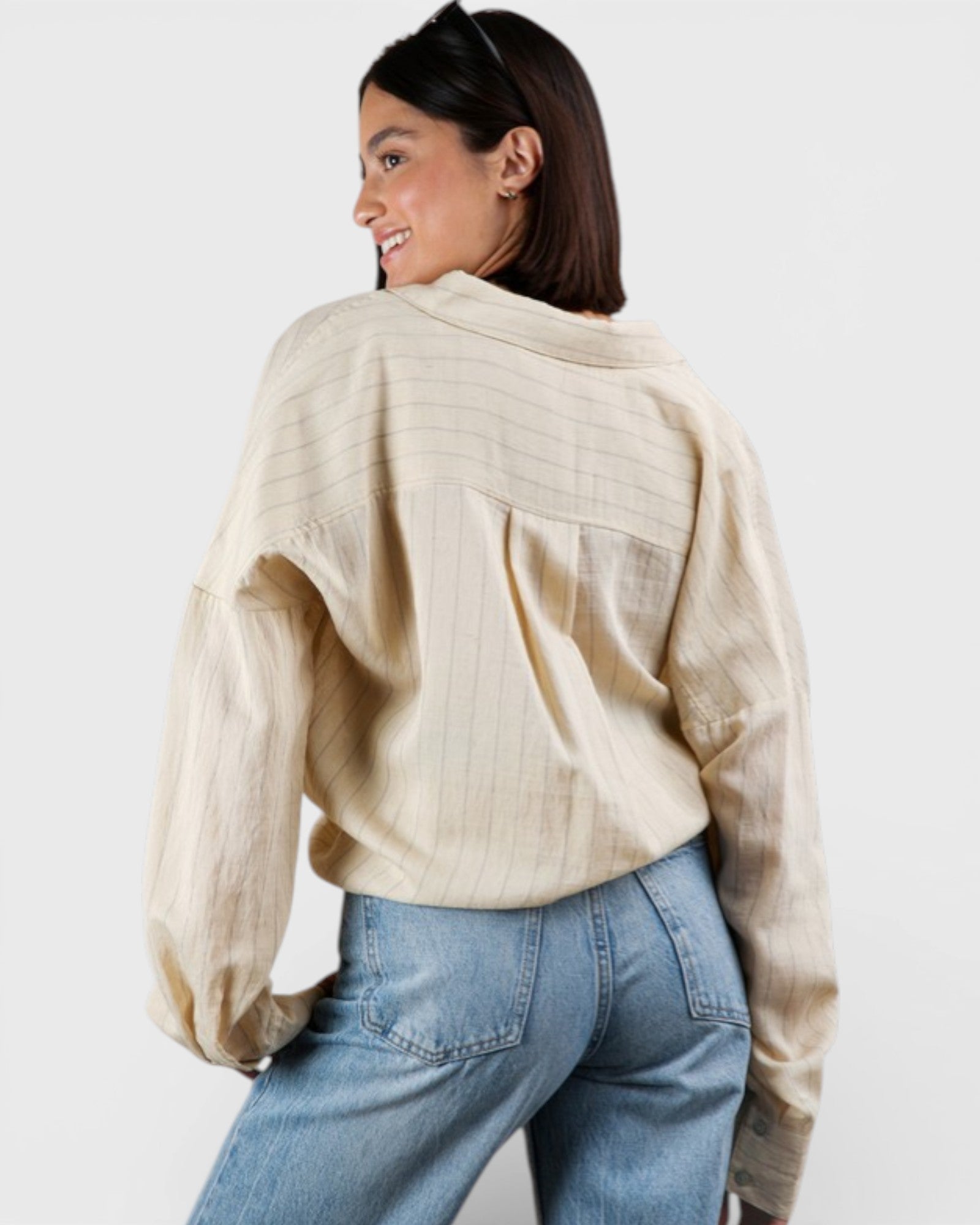 Woman wearing a beige sweater and blue jeans on a white background