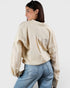 Woman wearing a beige sweater and blue jeans on a white background