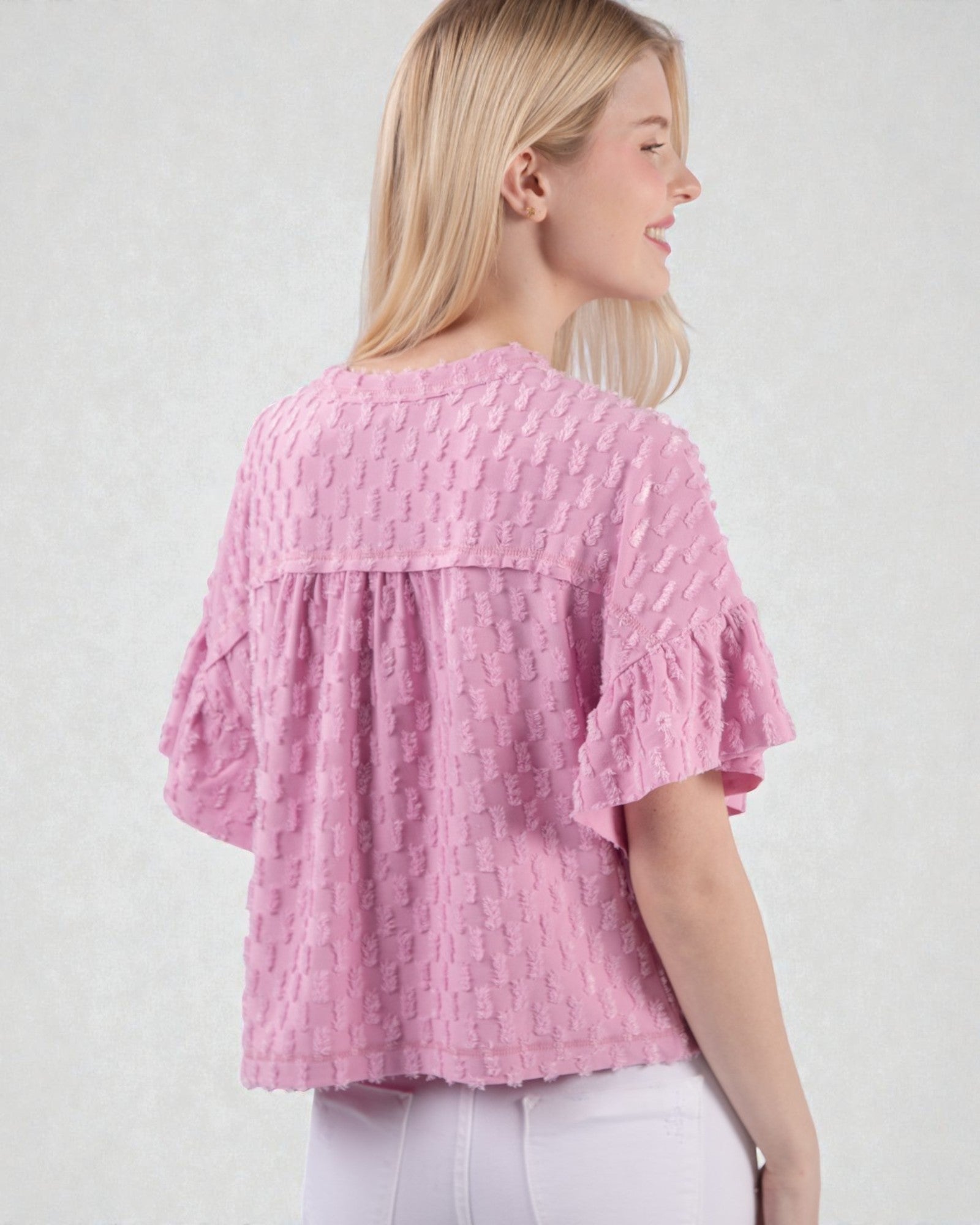 Woman wearing a pink textured blouse against a white background