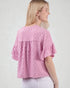 Woman wearing a pink textured blouse against a white background