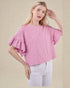 Woman wearing a pink textured blouse with ruffled sleeves on a beige background