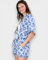 Woman wearing a blue and white patterned outfit on a plain background