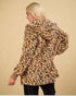 Person wearing a leopard print coat on a beige background