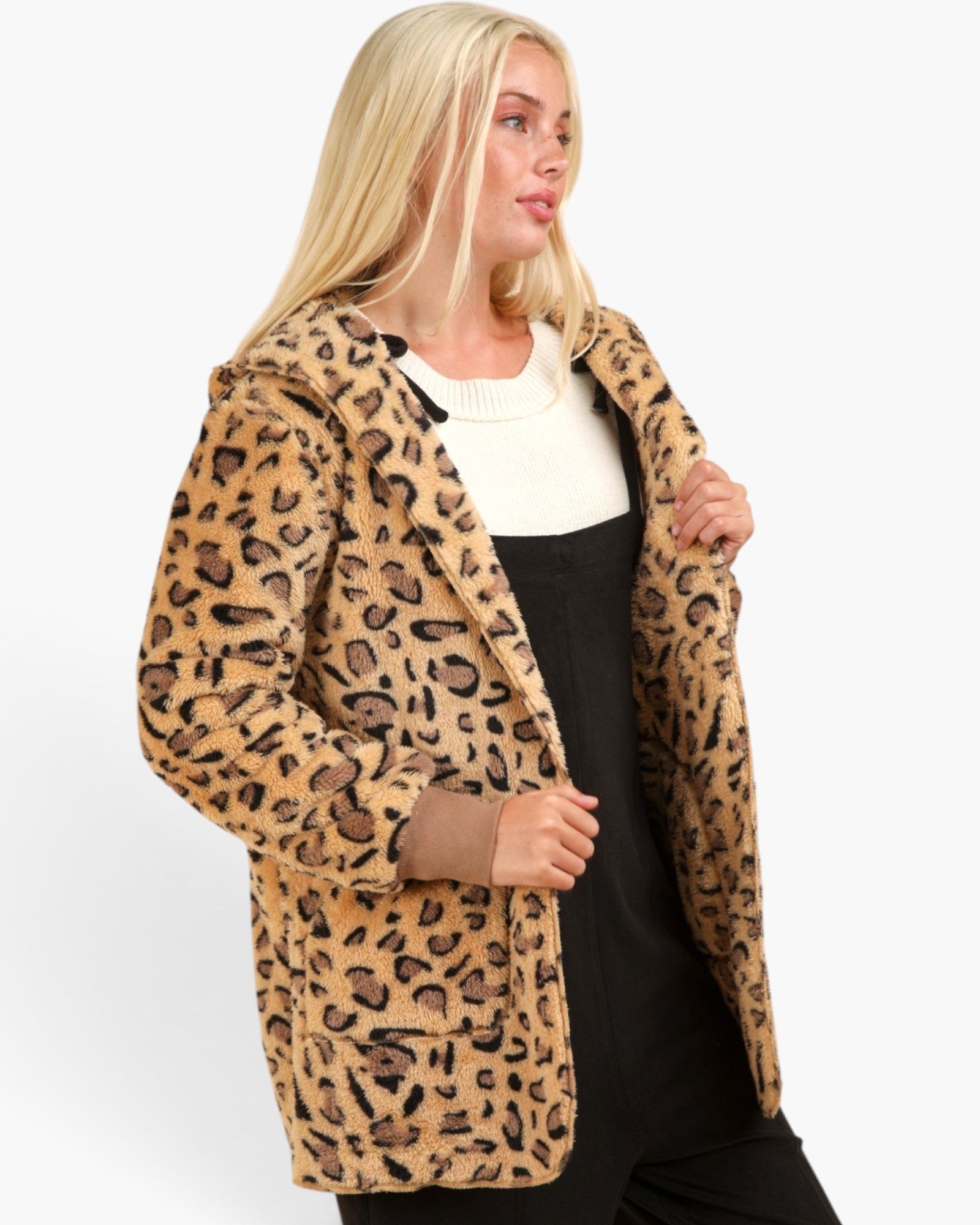 A blonde woman wearing a leopard print fuzzy hooded jacket over a black and white top, photographed against a plain light gray studio background.