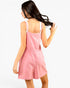A woman wearing a light pink sleeveless romper with thin shoulder straps and a gathered waist, shown from the back against a plain white background.