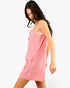 A woman wearing a pink sleeveless mini dress with a front flap pocket, photographed against a plain white studio background.