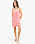 A woman modeling a pink sleeveless romper with a white trim at the neckline, front buttons, a drawstring waist, and front patch pockets, photographed against a plain white studio background.