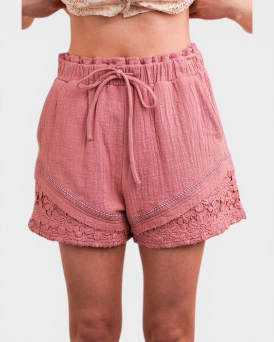 Pink shorts with lace trim worn by a person on a white background
