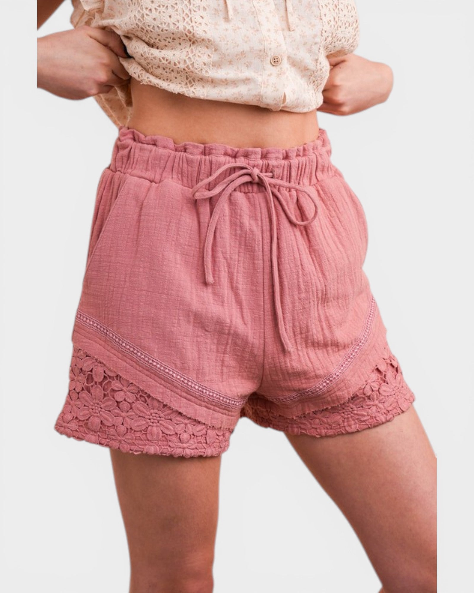 Pink shorts with lace trim worn by a person on a white background