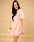 Woman wearing a pink dress with lace details on a beige background