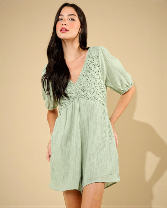 Woman wearing a light green dress with lace details against a beige background