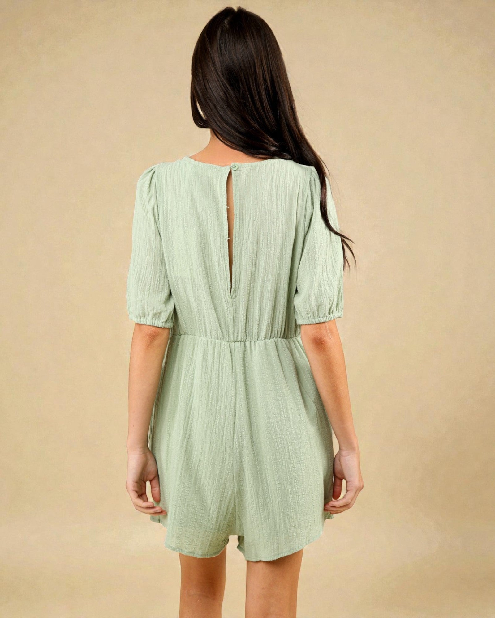 Woman wearing a light green dress with a plain background