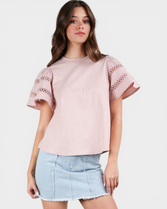 Woman wearing a pink blouse with lace details and a denim skirt on a white background